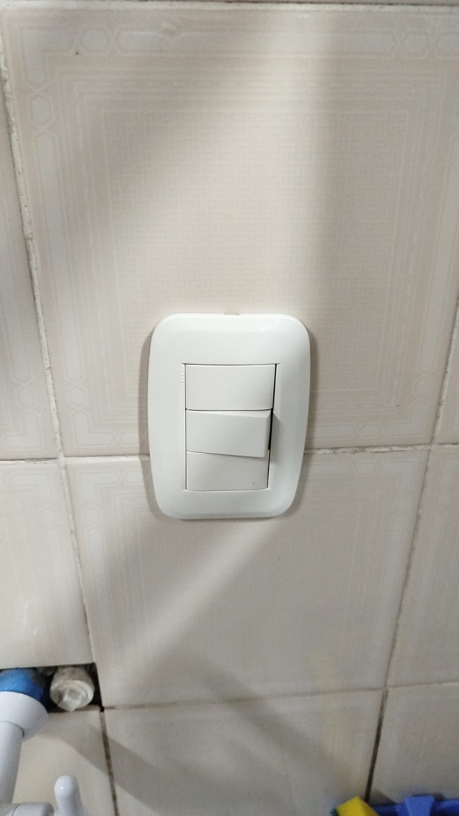 interruptor de três teclas branco instalado em parede de azulejos claros, provável serviço elétrico realizado 